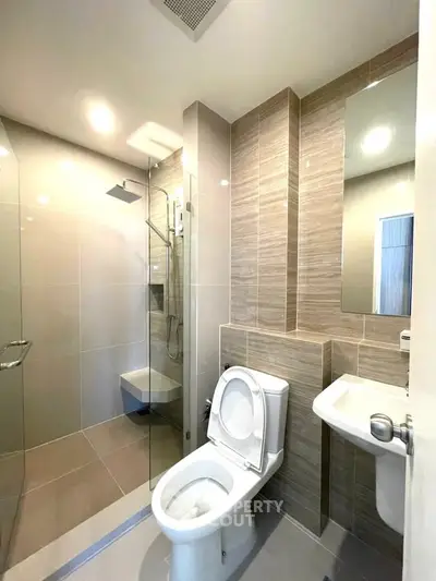 Modern bathroom with sleek design, featuring a glass-enclosed shower and contemporary fixtures.