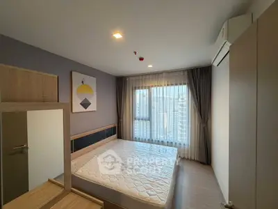 Modern bedroom with large window and city view, featuring stylish decor and ample natural light.