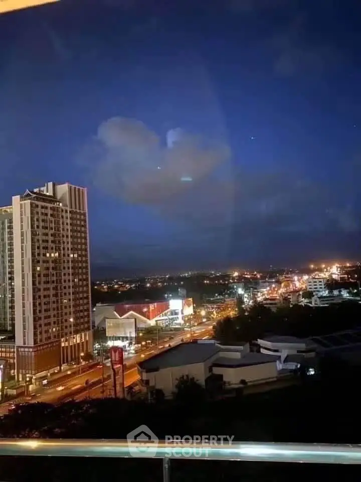 Stunning cityscape view from a high-rise balcony at night, showcasing vibrant city lights and modern architecture.