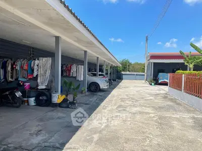Spacious carport with laundry area in a residential property under clear blue skies.