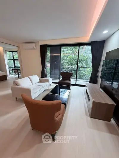 Spacious living room with modern furniture and large windows offering lush garden views.