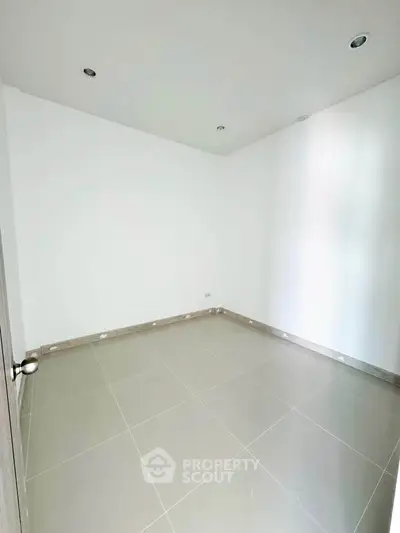 Spacious empty room with tiled flooring and white walls, perfect for customization.
