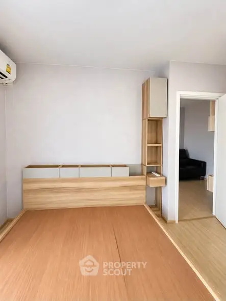 Modern minimalist bedroom with wooden flooring and built-in storage solutions.
