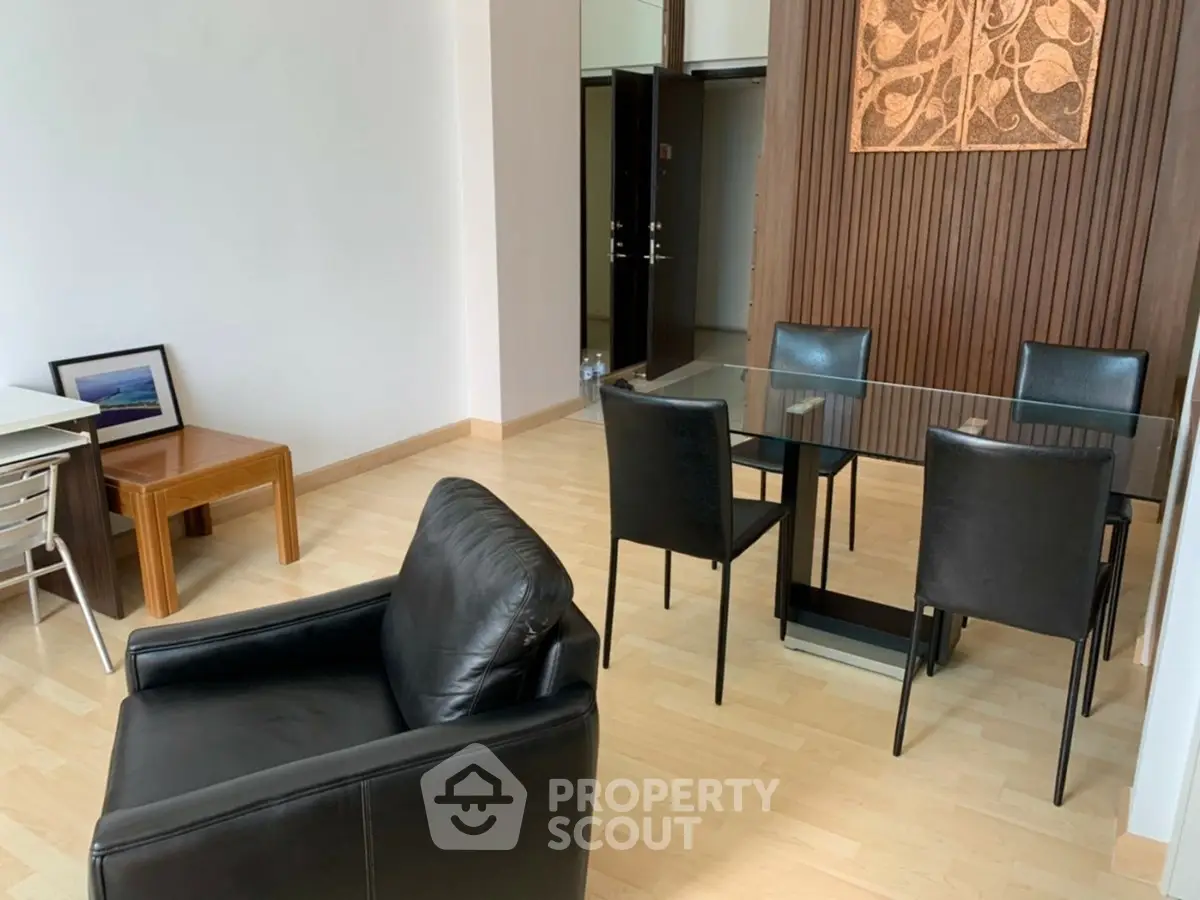 Modern dining area with glass table and leather chairs in a stylish apartment.