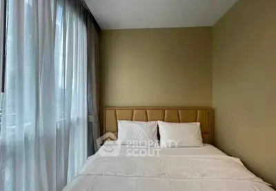 Cozy bedroom with plush bed and large window offering natural light in modern apartment.