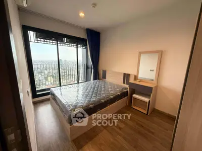 Modern bedroom with city view and balcony access in high-rise apartment.