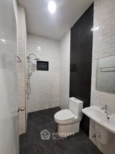 Modern bathroom with sleek design, featuring a shower, toilet, and sink with elegant tile work.