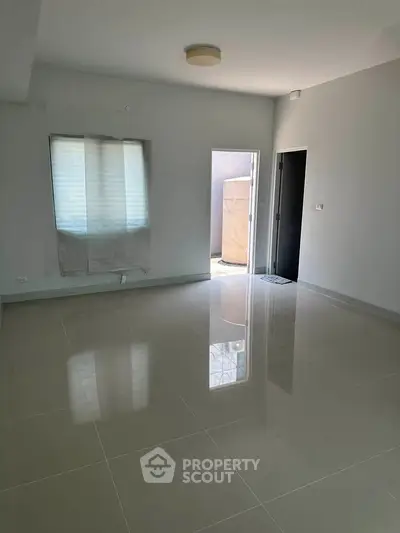 Spacious unfurnished living room with glossy tiled floors and natural light.