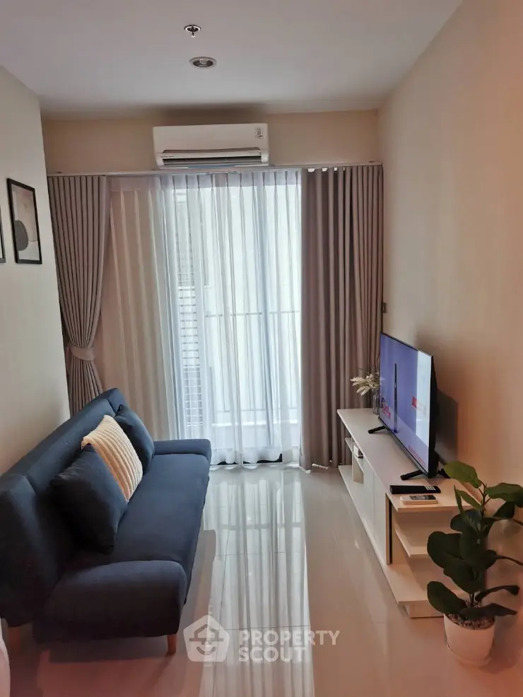 Modern living room with sleek sofa, TV, and large window for natural light.