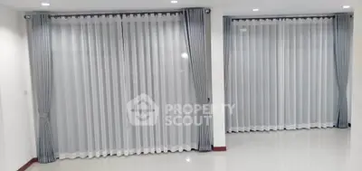 Spacious room with large windows and elegant curtains, perfect for natural light.