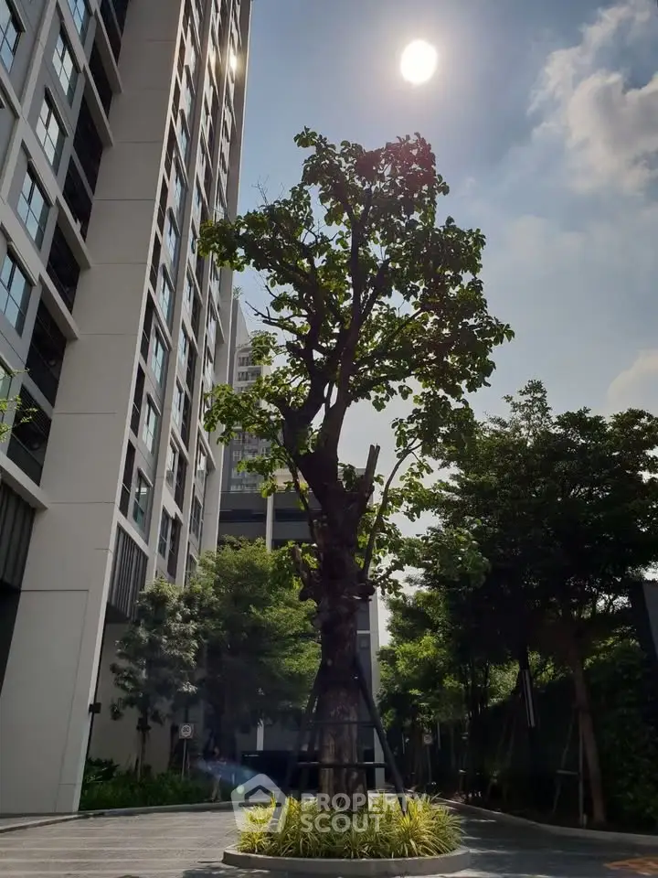 Modern high-rise building with lush landscaping and clear blue sky