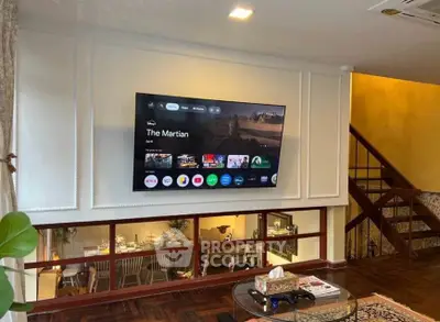 Stylish living room with mounted TV and elegant decor, featuring a cozy dining area below.