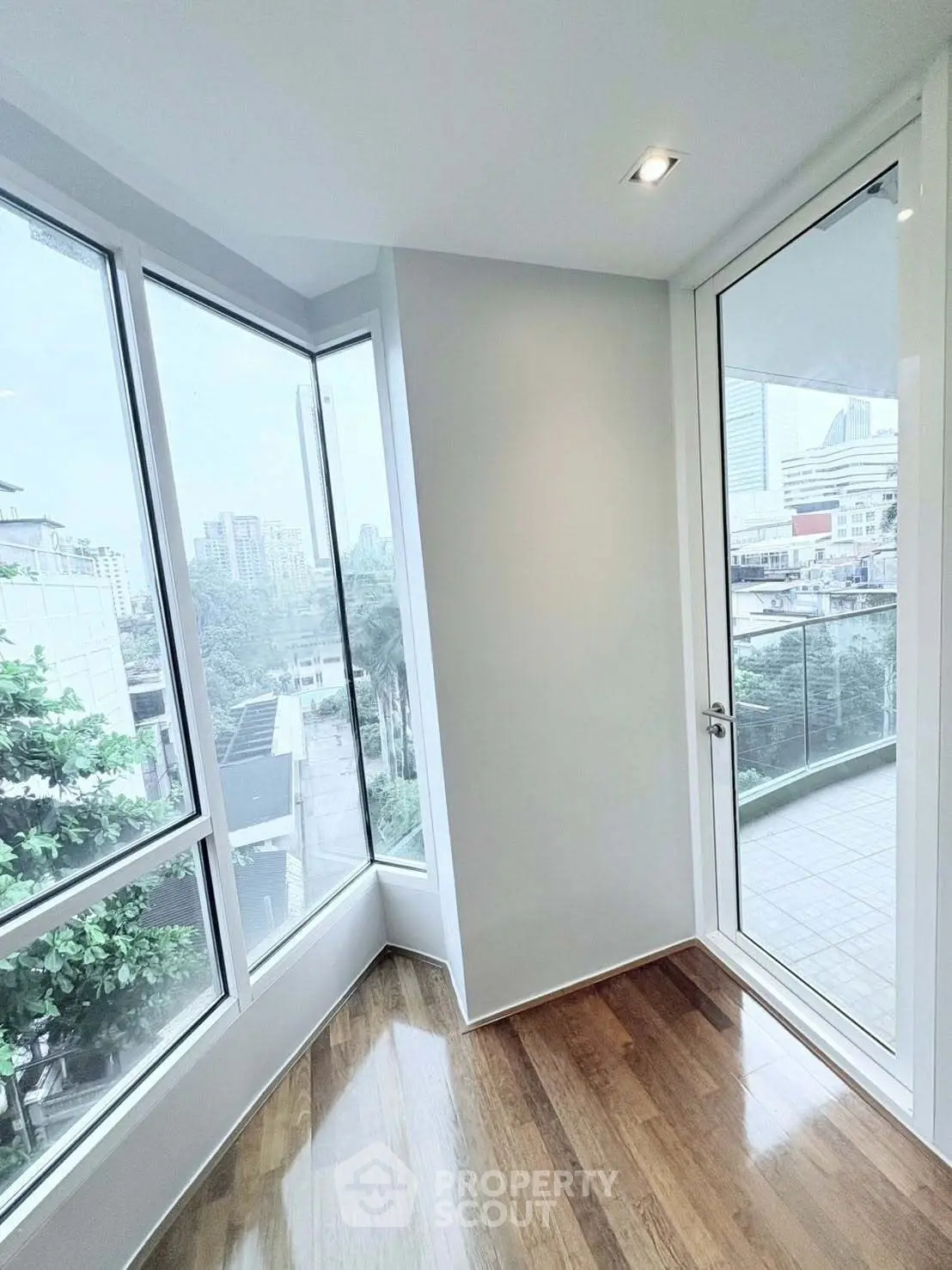 Bright corner unit with floor-to-ceiling windows and city view balcony access.