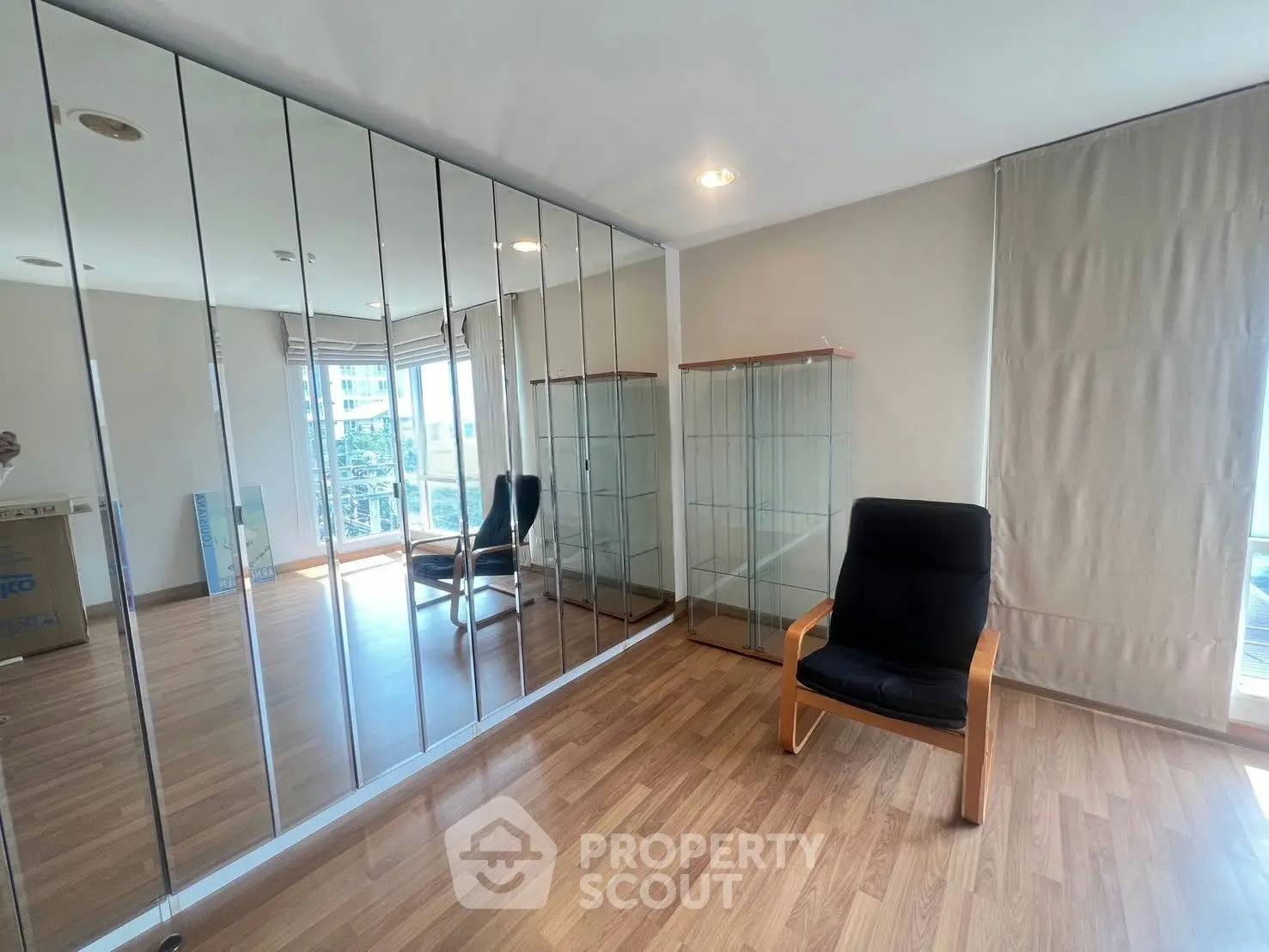 Spacious room with mirrored wall and modern chair, perfect for versatile living space.