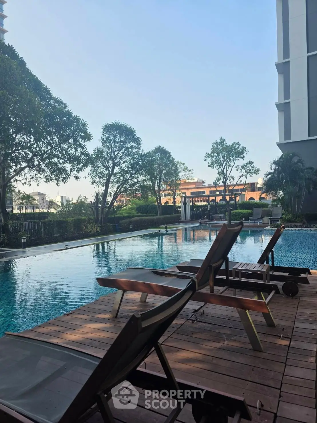 Luxurious outdoor pool area with sun loungers and lush greenery in a modern residential complex.