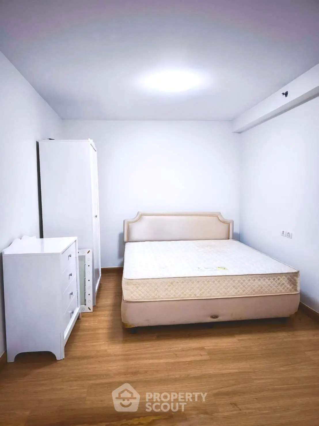 Spacious bedroom with minimalist design and wooden flooring
