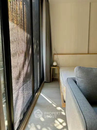 Bright bedroom with large window and cozy seating area, perfect for relaxation.