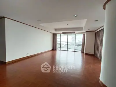 Spacious living room with large windows and wooden flooring in modern apartment.
