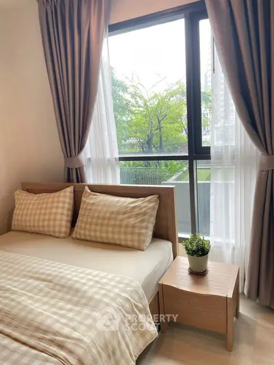 Cozy bedroom with large window and garden view, featuring stylish checkered bedding and elegant curtains.