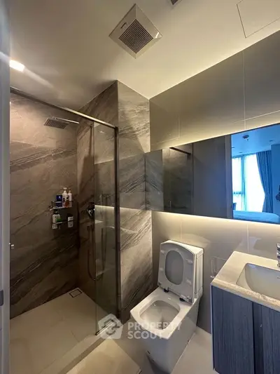 Luxurious modern bathroom with glass shower and sleek fixtures in upscale apartment.