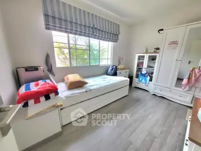 Bright and cozy bedroom with modern furnishings and large window view.