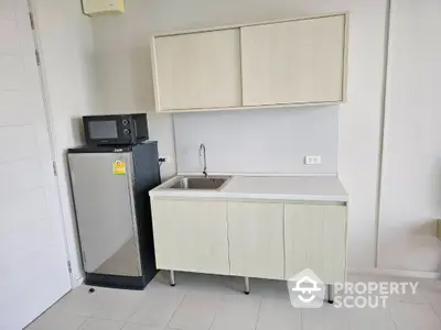 Modern minimalist kitchen with compact fridge and microwave