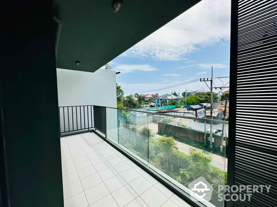 Spacious balcony with glass railing offering a scenic urban view, perfect for relaxation.