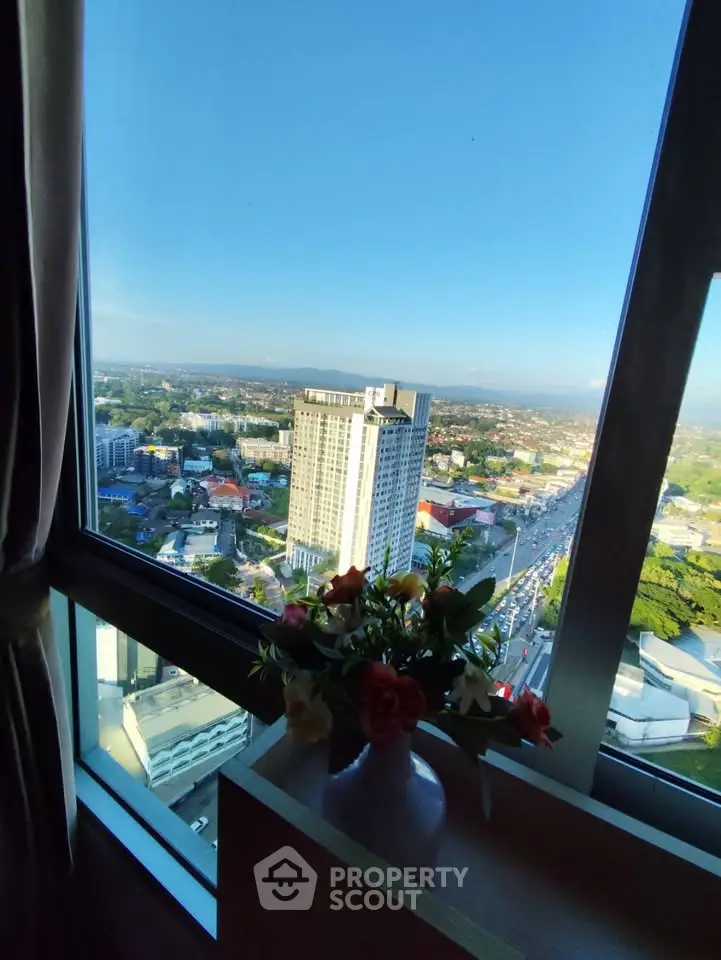 Stunning high-rise view from a modern apartment window with cityscape and clear blue sky.