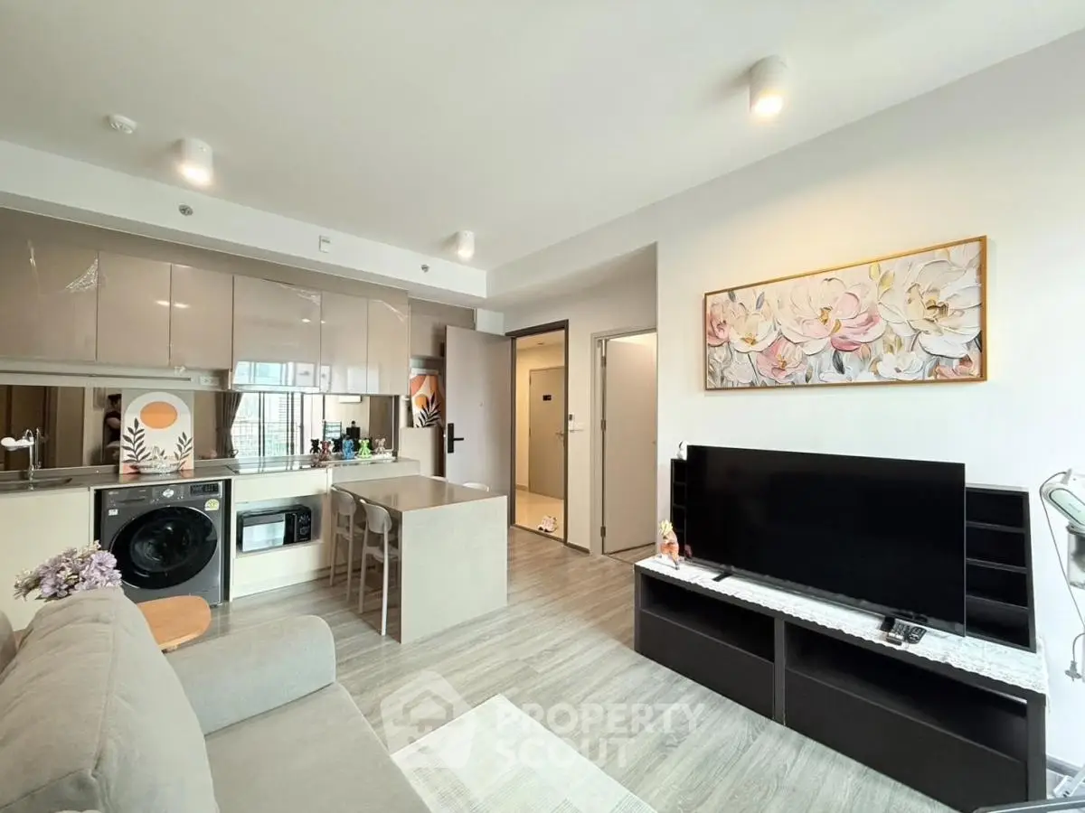 Modern open-plan living room with kitchen, featuring sleek design and natural light.
