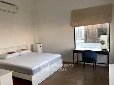 Spacious bedroom with modern furnishings and large window for natural light.