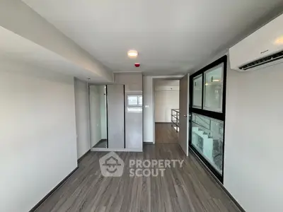 Modern bedroom with sleek flooring and built-in wardrobe, featuring large windows for natural light.
