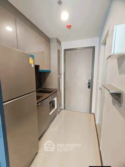 Modern compact kitchen with sleek appliances and stylish cabinetry in a contemporary apartment.