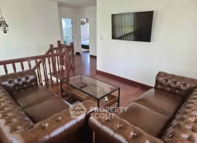 Elegant living room with leather sofas and wall-mounted TV, featuring wooden flooring and modern decor.