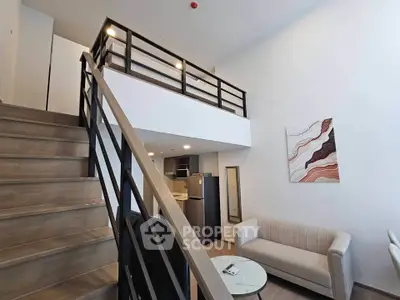 Modern loft apartment with stylish staircase and cozy living area, featuring contemporary furniture and high ceilings.