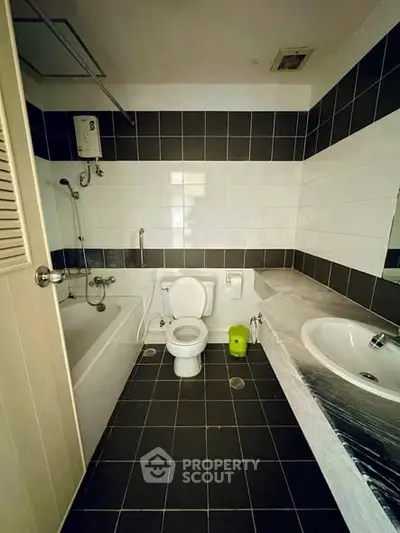 Modern bathroom with bathtub and sleek black and white tiles, featuring a compact layout.