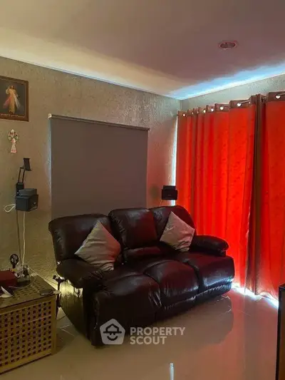 Cozy living room with leather sofa and vibrant red curtains, perfect for relaxation.
