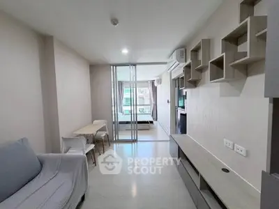 Modern living room with sleek furniture and sliding glass doors leading to a bedroom.