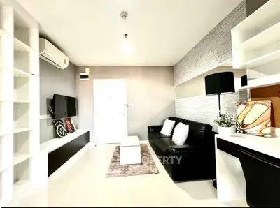 Modern living room with sleek design, featuring a black sofa, wall-mounted TV, and stylish shelving.