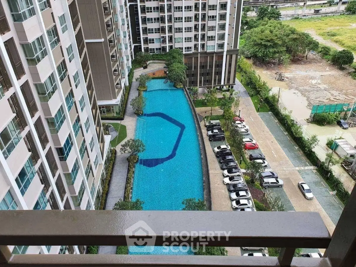 Stunning aerial view of modern apartment complex with pool and parking area.
