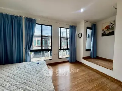 Spacious bedroom with large windows and wooden flooring in modern apartment