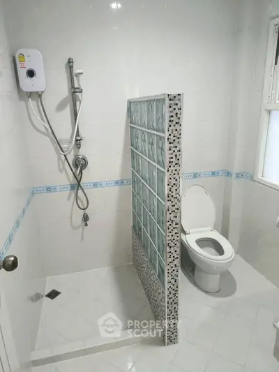 Modern bathroom with shower and toilet, featuring a glass block partition for privacy.