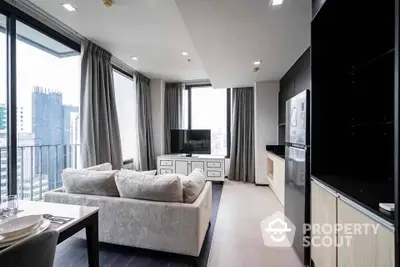 Modern living room with large windows and city view, featuring a cozy sofa and sleek TV setup.