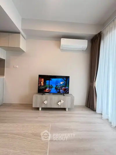 Modern living room with sleek TV setup and air conditioning, featuring elegant curtains and light wood flooring.