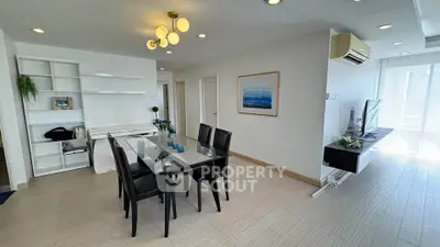 Modern dining area with sleek glass table and stylish black chairs in a bright open-plan living space.