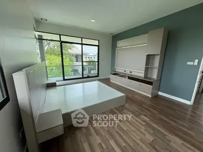 Spacious modern bedroom with large windows and built-in storage, offering a serene view.
