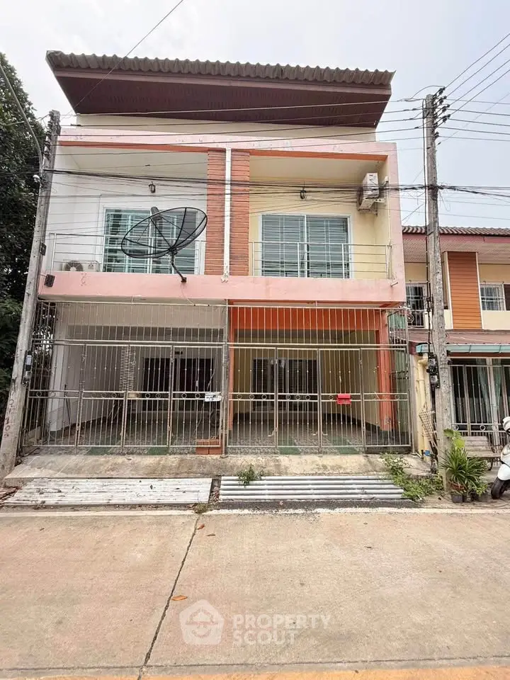 Charming two-story townhouse with balcony and gated entrance in a quiet neighborhood.