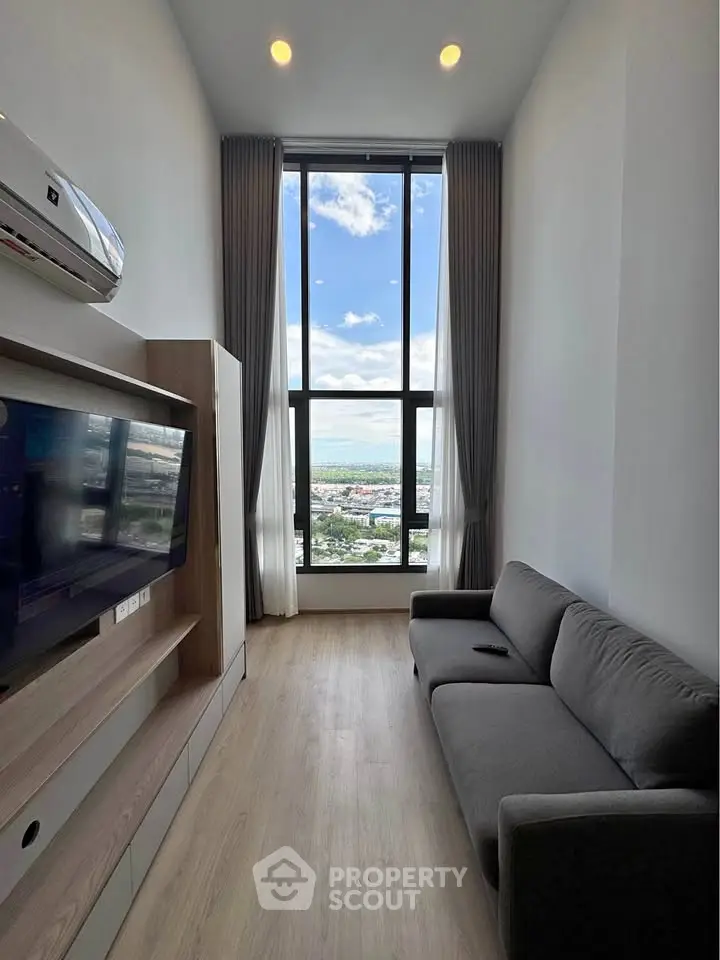 Modern living room with floor-to-ceiling window offering stunning city and sea views.