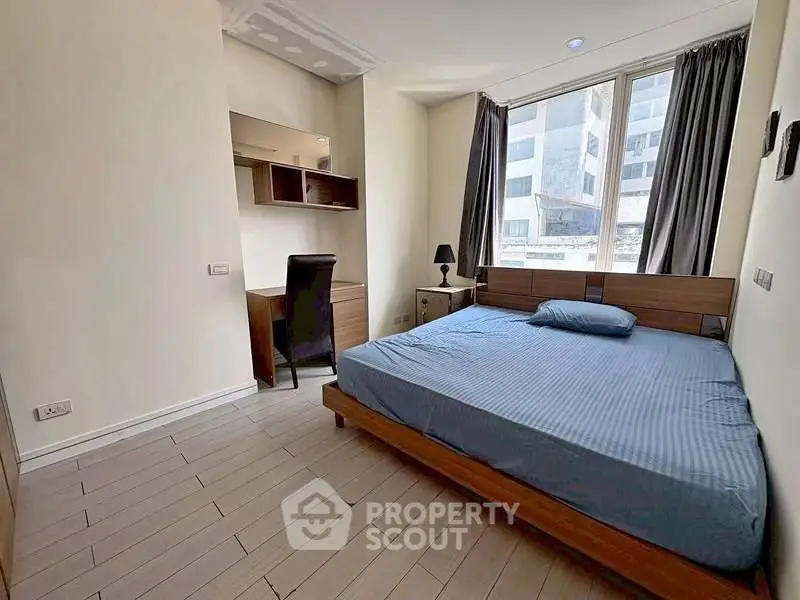 Modern bedroom with large window and stylish furniture in urban apartment.