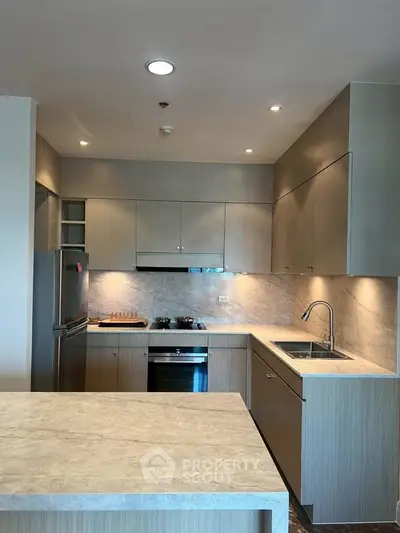 Modern kitchen with sleek cabinetry, built-in oven, and elegant marble countertops.