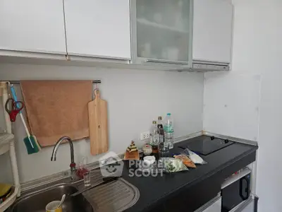 Modern kitchen with sleek cabinets and countertop, featuring a sink and cooking essentials.